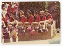 A Group of Majorettes sit with Members of the Marching Band, circa 1980