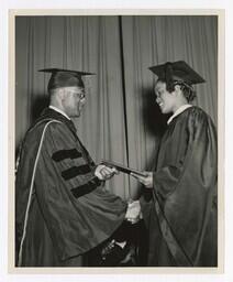 A Graduate Shakes Hands With James P. Brawley on stage at Commencement, circa 1965