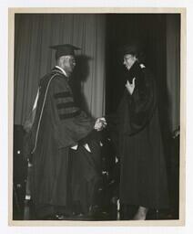 A Graduate Shakes Hands With James P. Brawley on stage at Commencement, circa 1965