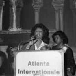 Vivian Malone Jones speaks from an "Atlanta Internationale" podium at an event.