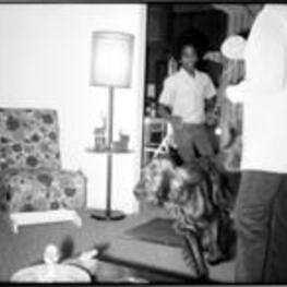 An unidentified boy chases an Irish Setter through a living room past a young girl.