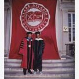 Dr. Thomas Cole poses with another man on the steps of building in front of a banner "Clark Atlanta University" at commencement.