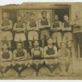 Outdoor group portrait of young men wearing athletic wear, one man holding a basketball.