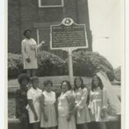 Outdoor group portrait of women in front of the historic site sign of Bethel AME Church.