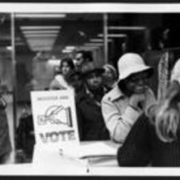 A group of people wait in line to register and vote.