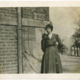 A woman stands in front of a building with three others in the background.