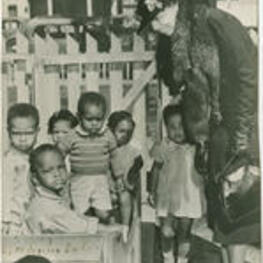 Eleanor Roosevelt leans over and smiles at unidentified children. Written on recto: Los Angeles Cal. March 1937
