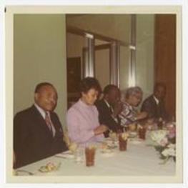 Edward A. Jones and others sit at a luncheon table. Written on verso: E.A. Jones, Beulah Gloster, Howard Thurman, O. Watson, M.N. Watson