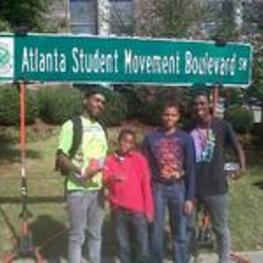 A group of young men stand under the Atlanta Student Movement Boulevard sign during the dedication celebration.