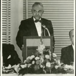 Willis J. Hubert stands behind a podium. Written on verso: Dr. Willis J. Hubert, Academic Dean. Founder's Day banquet, 1973.
