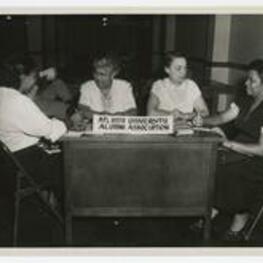 Women sit at a desk beside a sign reading "Atlanta University, Alumni Association".