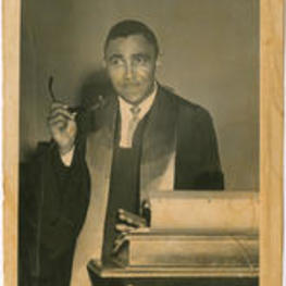 A portrait photo of Joseph E. Lowery posing behind a church alter holding his glasses.