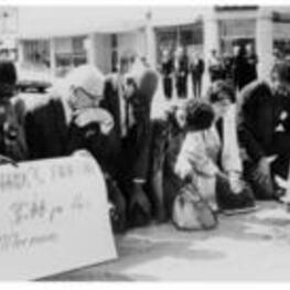 Ruby D. Smith and unidentified people kneel and pray with protest signs for William Lewis Moore, a CORE member who was shot in Keener Alabama during a protest march.