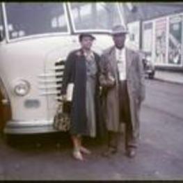 Levi and Jewell Terrill stand in front of a charter bus.