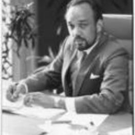 Portrait of Oscar Lewis Harris, Jr. seated behind his desk.