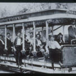 Men ride a trolley in Altanta. Text from slide presentation: During the 1880s, the Atlanta Street Railroad Company extended its trolley system toward the east. For the first time, neighborhood residents could enjoy the convenience of riding the trolley to downtown Atlanta.