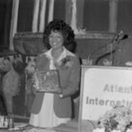 Vivian Malone Jones smiles and holds a plaque given to her at an event.