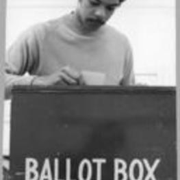 View of an unidentified man placing his vote in a Fulton County ballot box.