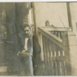 Eugene Dibble sits on steps in front of a house. Written on verso: "Eugene Dibble."