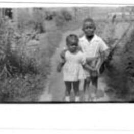 Harrison Jordon and an unidentified neighbor girl stand outside of a house.