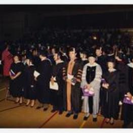 Indoor view of men and women wearing caps and gowns.