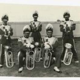 Outdoor group portrait of 5 young men wearing marching band uniforms, view of tubas.