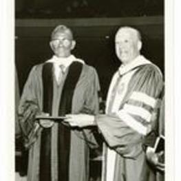 Written on verso: Dr. Cheikh Anta Diop (Left) receives the honorary degree of Doctor of Humane Letters, conferred upon him by Dr. Hugh M. Gloster (Right), President of Morehouse College, during the King Memorial Convocation held April 5, 1985 at 11 A.M. in the great name of the Martin Luther King, Jr. International Chapel on the Morehouse College Campus.