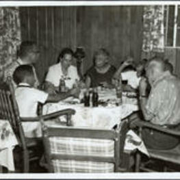 Dr. and Mrs. Brazeal dine around a table with others. Written on verso: July 1961 - Link Family Picnic at the country home of connecting Link and Link Richard Hackney. Extraneous note: L to R: Dr. Brazeal, Mrs. Brazeal, Mrs. Sadie Harris.
