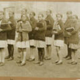 A group of girls hold classbooks and prepare for school.