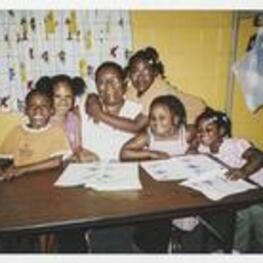 A group of children sit with Carolyn Christian. A young girl, Christian Stembridge has her arms wrapped around Ms. Christian. Written on verso: Vacation Bible School - 2007. Jordan McKnight, [Amiyah] McCoy, Carolyn Christian (adult), Christian Stembridge (w/arm around Carolyn's neck, Kyla-Key Lewis, Makayla Lewis.