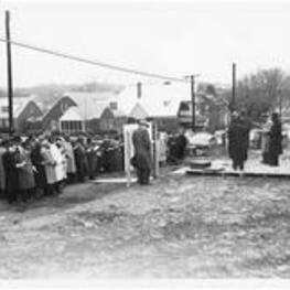 A group gathers and listens to Benjamin Mays speak at the ITC dedication with James Brawley and others stand on stage. Written on verso: Dedication service for the new ITC site February 4, 1960