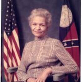 Grace Towns Hamilton sits in a chair with the American flag and the Georgia state flag behind her.