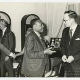 Edward A. Jones speaks with an unidentified man while people in the background shake hands.