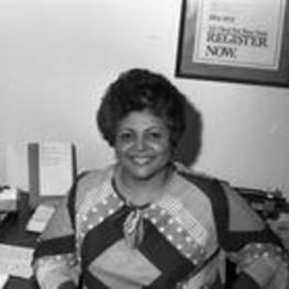 An unidentified woman smiles and sits at her desk in a VEP office.