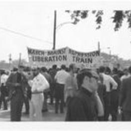 A group of people prepare for the start of the march and hold a large banner that reads "March Against Repression Liberation Train, SCLC." Written on accompanying document: March Against Repression 5-23-70 began at Ebernezer - ended Morehouse College - marchers assymbling.