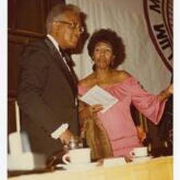 View of a man and woman speaking. Written on verso: "Dr. Robert Threatt and Mrs. Helen Threatt at Man of the Year Awards Ceremony".