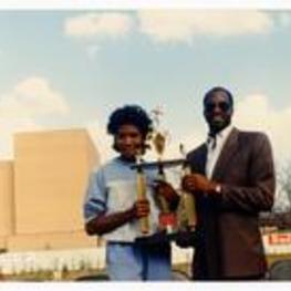 Photograph of student athlete and Edwin Moses. Written on verso: Edwin Moses Homecoming Oct. 27, 1984.