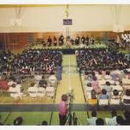 Indoor arial view of men and women seated in gymnasium.
