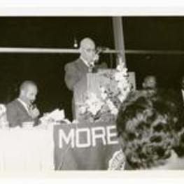 A man delivers a speech at a podium. Written on verso: Alvin H. Lane, Chicago Morehouse Founders' Day Dinner 1963