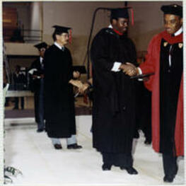 An unidentified man shakes hands with a faculty member as he receives his diploma.