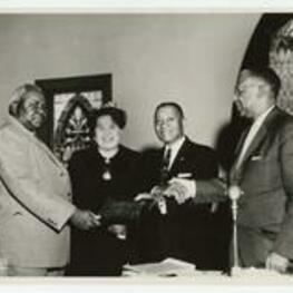 Indoor group portrait of 3 men and 1 woman. Written on verso: presentation of a plaque ceremony to J. Herbert Touchstone at a business session of the West Texas Annual Conference at St. Andrews Church, Fort Worth, Texas, May 5, 1962.