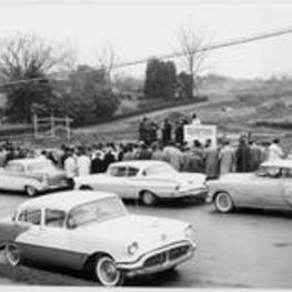 A group gathers outside by a row of cars for the ITC groundbreaking dedication. Written on verso: Dedication service for the new site February 4, 1960.