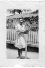 An unidentified woman stands on the sidewalk and poses next to a parking meter.