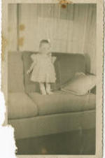 Victoria Yancey, a child,  stands on a couch. Written on verso: Kappa-Alpha-Psi; Victoria Elizabeth Yancey.
