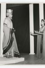 View of man and woman actors wearing costumes on stage.