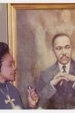 Coretta Scott King stands beside a portrait of Martin Luther King Jr.
