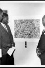 Three unidentified men admire artwork at the art exhibition opening.