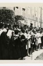 A view of men and women, wearing choir robes, singing on stage at commencement.