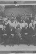 Men and women, part of faculty and staff of Morris Brown College, gather for a portrait outside of a campus building.