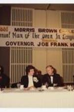 Indoor view of men and woman seated at buffet table, view of sign in background "1881 Morris Brown College 1983, Annual Man of the Year in Georiga Award Dinner Honoring Governor Joe Frank Harris".